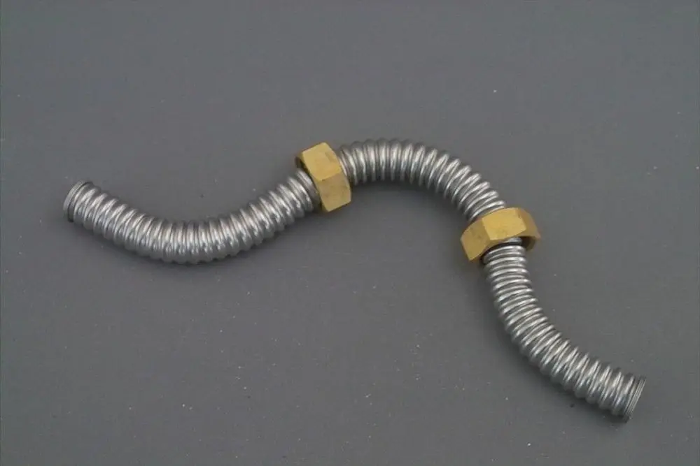 Vorgebogenen Metallrohr mit Gewinden an beiden Enden. Verbindungselemente aus Messing. Verwendung vermutlich in Heizungs- oder Installationssystemen von Brötje.