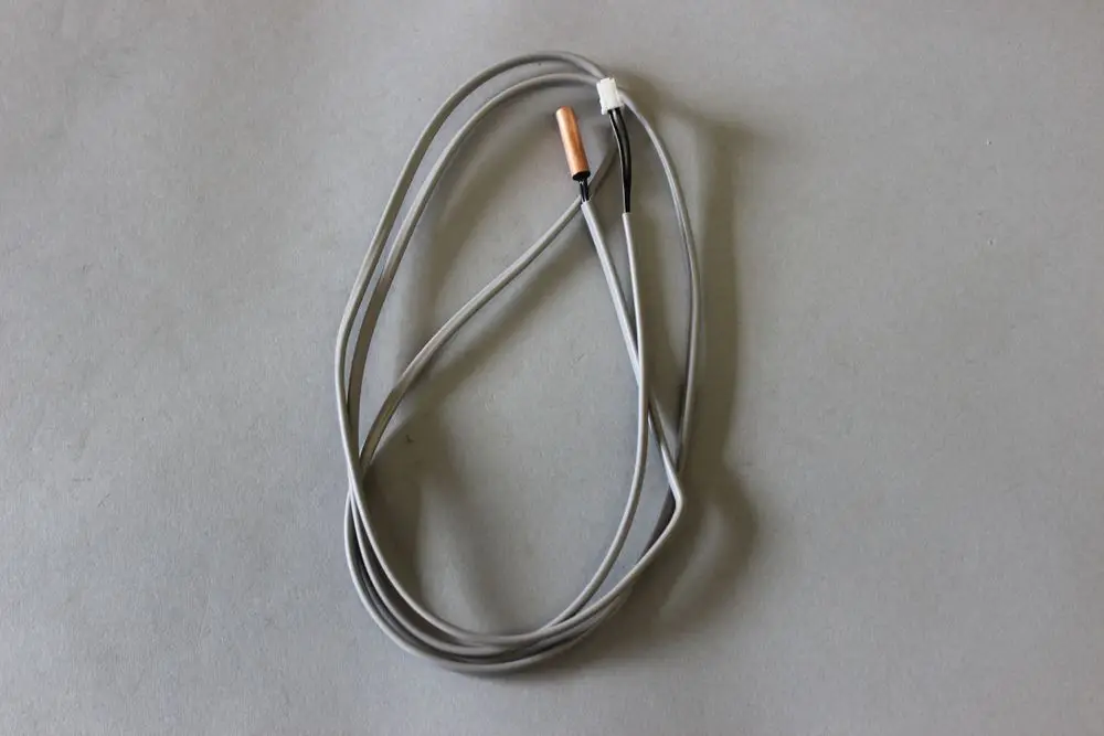 Graue, flexible Kabel mit zwei Anschlüssen, die einen Brötje Fühler bilden. Die Kabel sind schlank und verlaufen in einem leichten Bogen auf einem grauen Hintergrund.