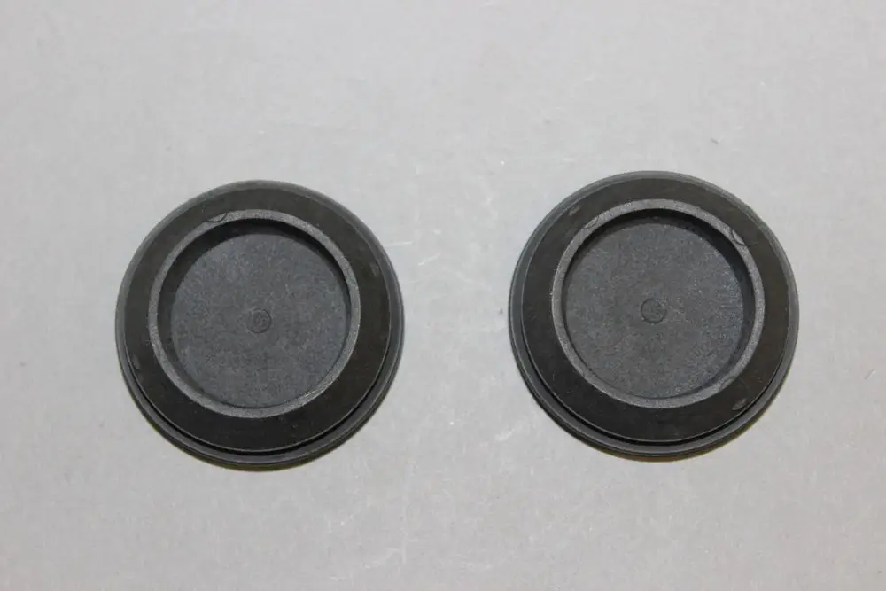 Zwei schwarze Kabeltüllen von Brötje auf grauem Hintergrund, mit einem flachen, runden Design und einer tiefen Innenvertiefung.