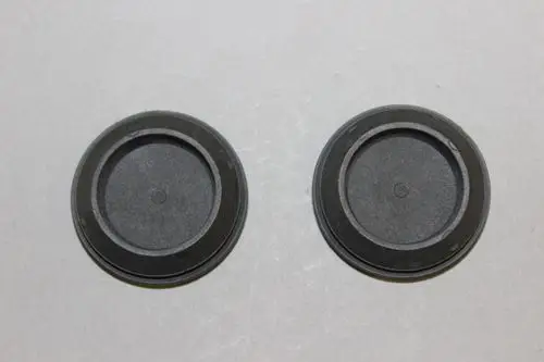 Zwei schwarze Kabeltüllen von Brötje auf grauem Hintergrund, mit einem flachen, runden Design und einer tiefen Innenvertiefung.