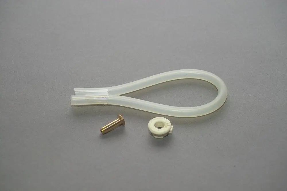 Transparenter Luftschlauch von Brötje, gebogen, mit einem kleinen weißen und einem metallischen Verbindungselement daneben, auf grauem Untergrund.