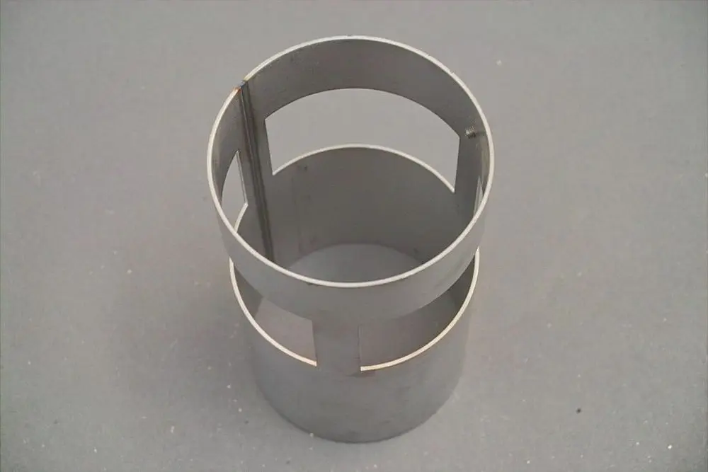 Rundes, graues Metallrohr mit zwei Öffnungen und zwei horizontalen Einschnitten. Teil eines Systems von Brötje zur Wärme- oder Wasserzirkulation.