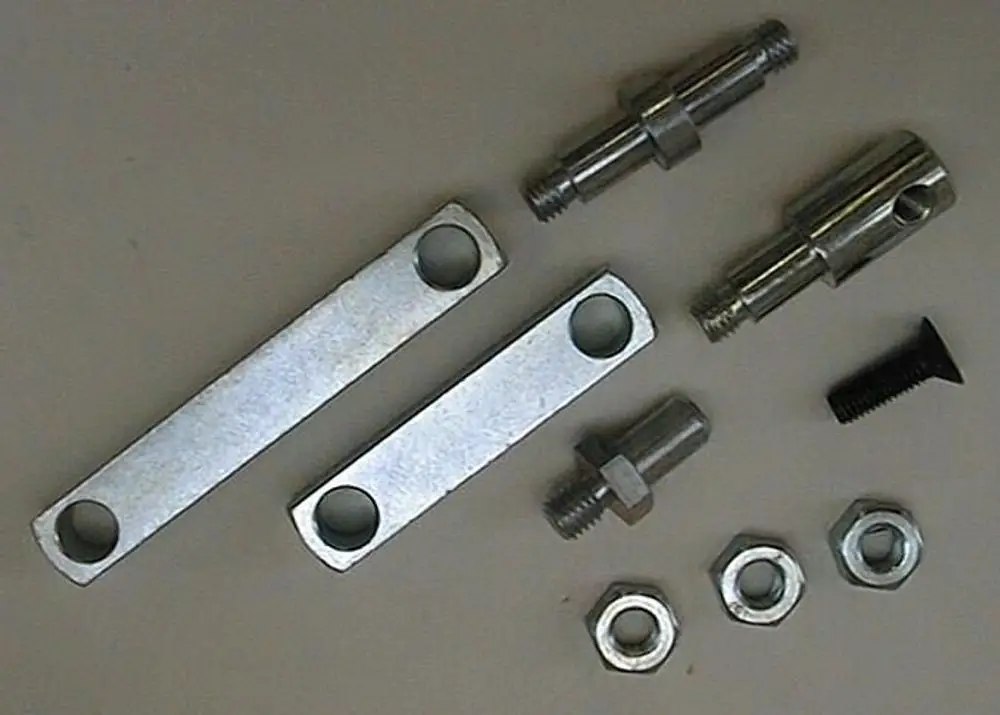Montagezubehör von Brötje, bestehend aus zwei Metallplatten mit Löchern, mehrere Gewindeteile, Schraube und Unterlegscheiben, auf hellem Untergrund angeordnet.