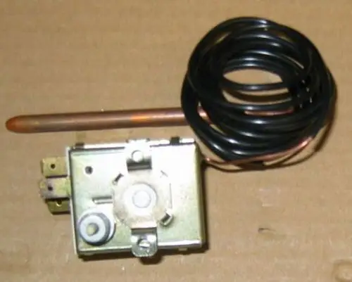 Sicherheitstemperaturbegrenzer von Brötje mit einem schwarzen Kabelspirale und einem Kupferrohr, montiert auf einer metallischen Grundplatte mit Anschlussklemmen.