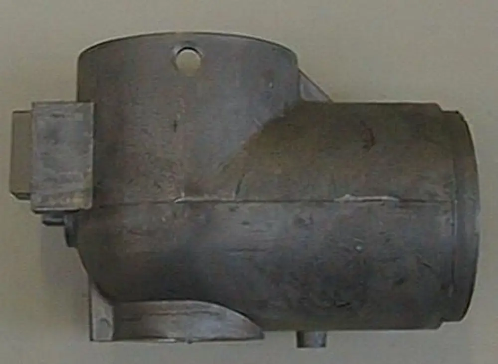 Brötje Schlitten, metallisches Bauteil mit runder Öffnung und seitlicher Anbaute, auf hellem Hintergrund.