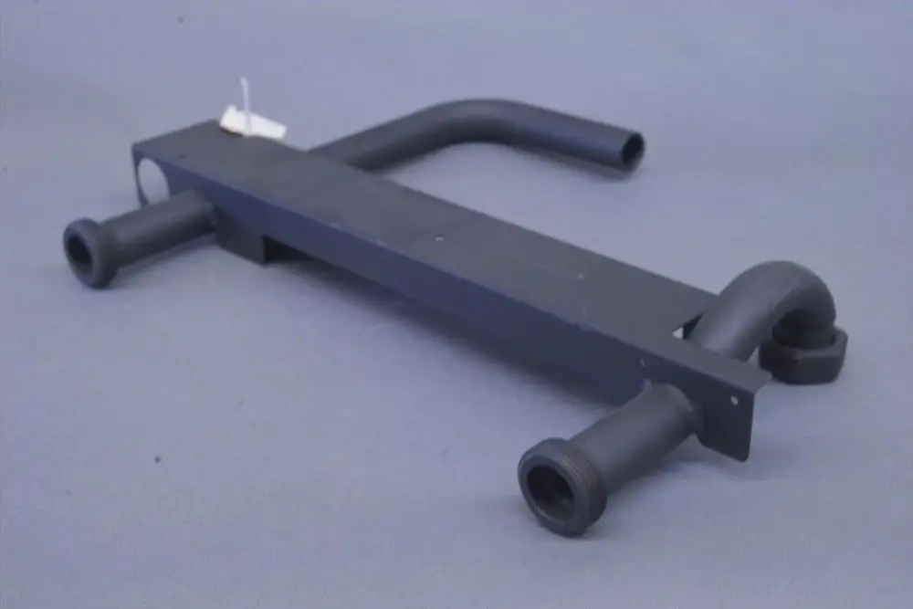 Brötje-Produkt mit flacher, rechteckiger Basis und zwei abgewinkelten Rohren an den Enden. Die Oberflächen sind in Schwarz gehalten.