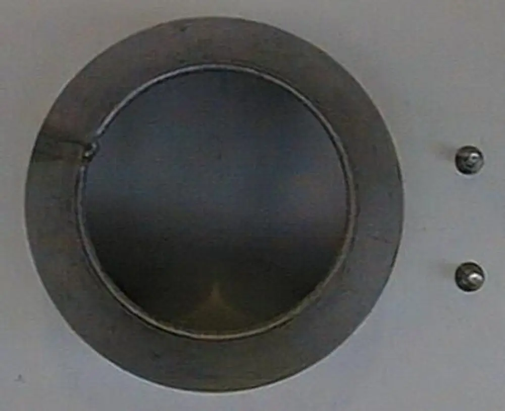 Rundes metallisches Bauteil mit offener Vorderseite, befestigt mit zwei Schrauben. Möglicherweise Teil eines Heizsystems von Brötje.
