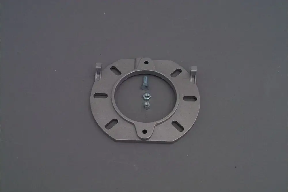 Brötje Kesselflansch aus Metall mit mehreren Bohrungen und Schrauben in der Mitte. Das Produkt hat einen runden Ausschnitt und Halterungen an den Seiten.