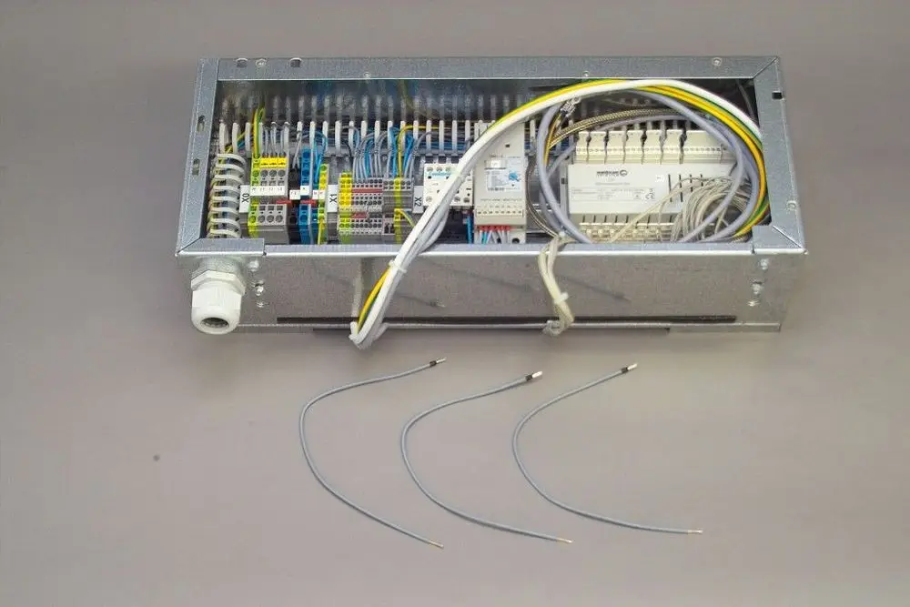 Brötje Elektroteil in einem Metallgehäuse mit offenem Zugang zu den Anschlussklemmen und mehreren Kabeln, die zur Verbindung nach außen ausgelegt sind.