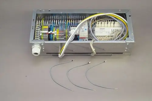 Brötje Elektroteil in einem Metallgehäuse mit offenem Zugang zu den Anschlussklemmen und mehreren Kabeln, die zur Verbindung nach außen ausgelegt sind.