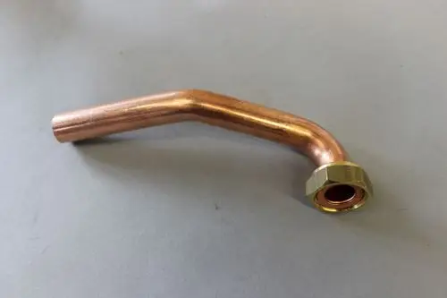 Kupferrohr mit einer Biegung und einem Anschlussstück aus Messing, zu verwenden in Heizungsanlagen der Marke Brötje.