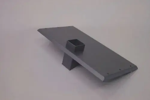Schwarzes, flaches Bauteil mit einer erhöhten Plattform und einem quadratischen Einsatz, vermutlich ein Teil von Brötje Heiztechnik, ohne sichtbare Maße oder Beschriftungen.