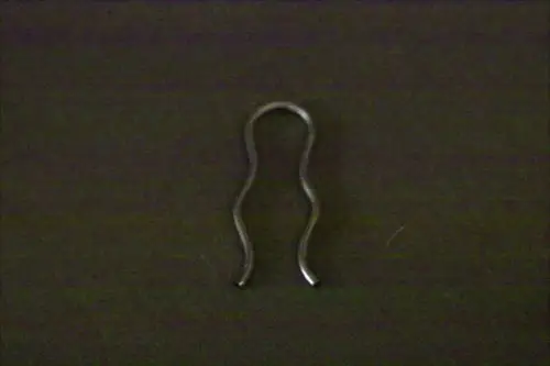 Brötje Klammer in geschwungener Form, aus Metall mit offenen Enden. Das Produkt liegt auf einem dunklen Hintergrund und zeigt eine einfache, funktionale Konstruktion.