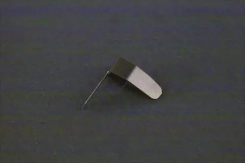 Metallene Feder von Brötje, in seitlicher Ansicht, auf dunklem Hintergrund. Die Feder zeigt eine gebogene Form und einen langen Stift.