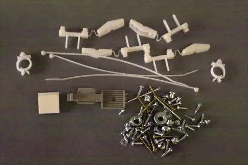 Brötje Schrauben-Set mit verschiedenen Kunststoff- und Metallteilen, einschließlich Schrauben, Unterlegscheiben und Kunststoffclips, auf grauem Hintergrund angeordnet.