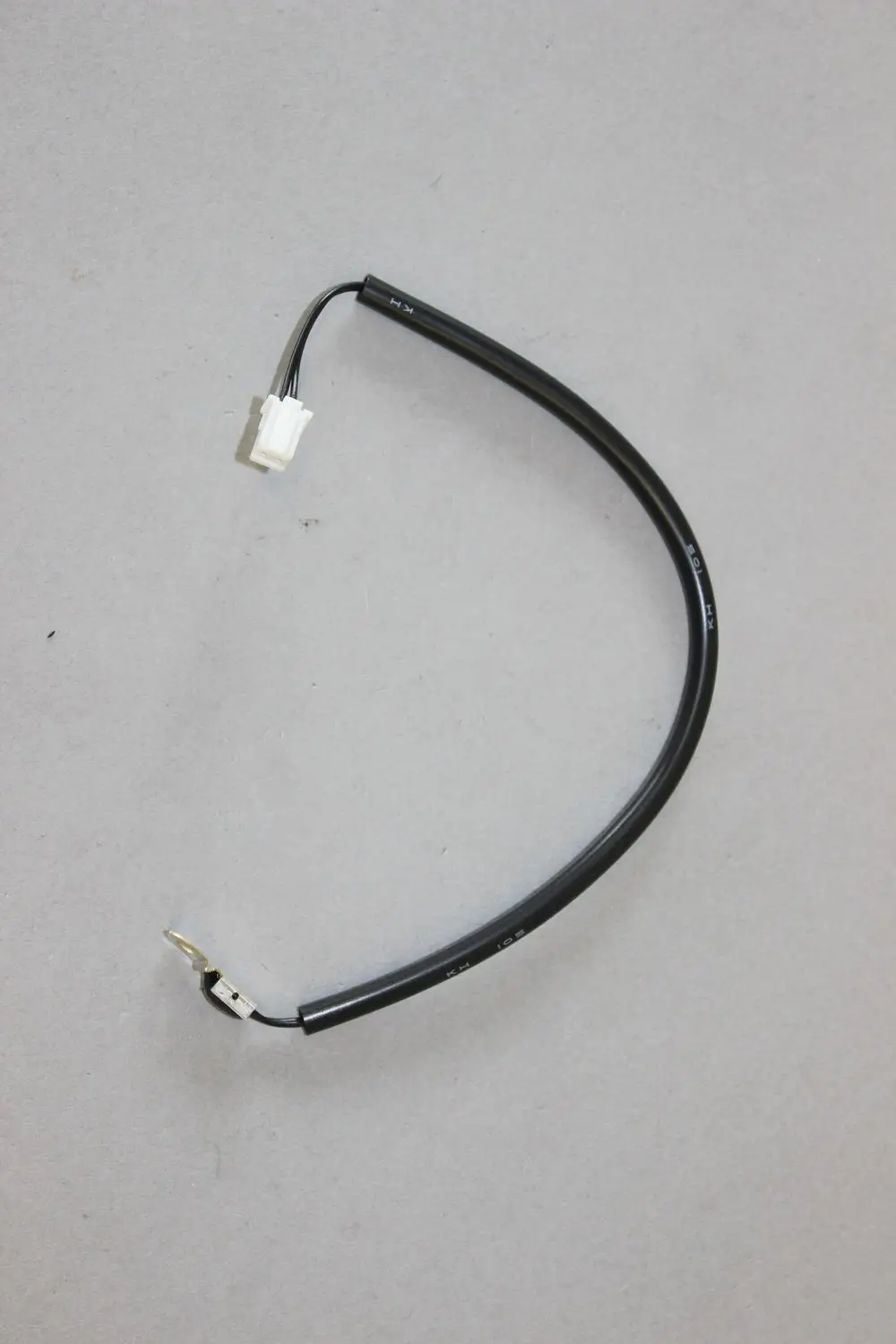 Brötje Fühler mit einem weißen Anschluss sowie einem schwarzen Kabel, das zu einem Verbindungselement führt. Klar abgegrenzte Drähte sind sichtbar.