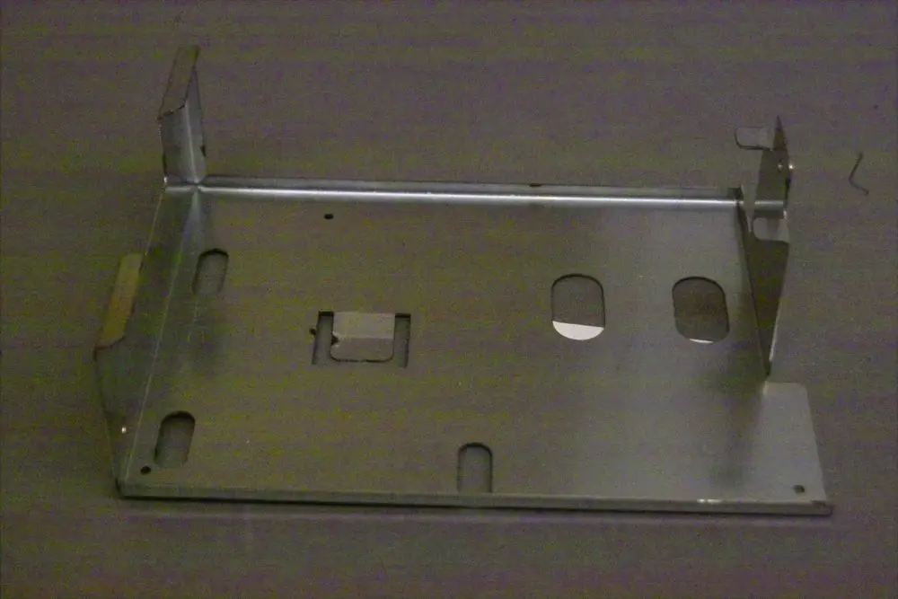 Metallischer Träger von Brötje mit mehreren Ausschnitten und Befestigungsmulden. Geeignet für die Aufnahme von Platinen oder ähnlichen Komponenten.