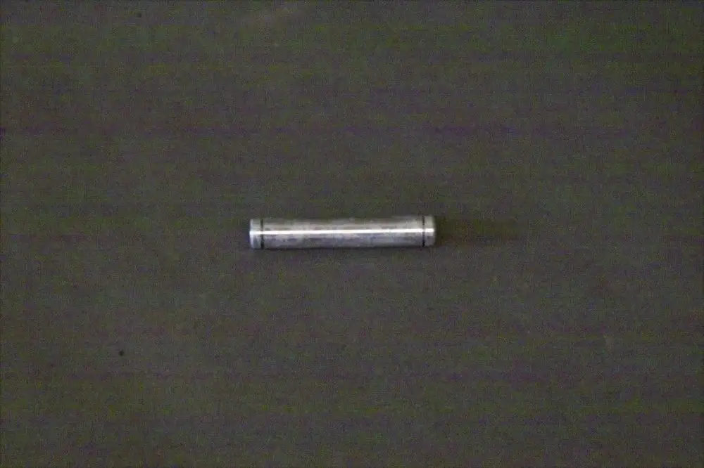 Brötje Bolzen, länglicher metallischer Gegenstand auf dunklem Hintergrund, mittig platziert.