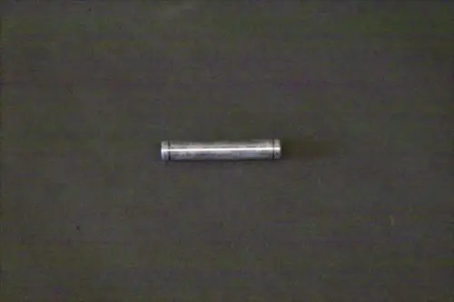 Brötje Bolzen, länglicher metallischer Gegenstand auf dunklem Hintergrund, mittig platziert.