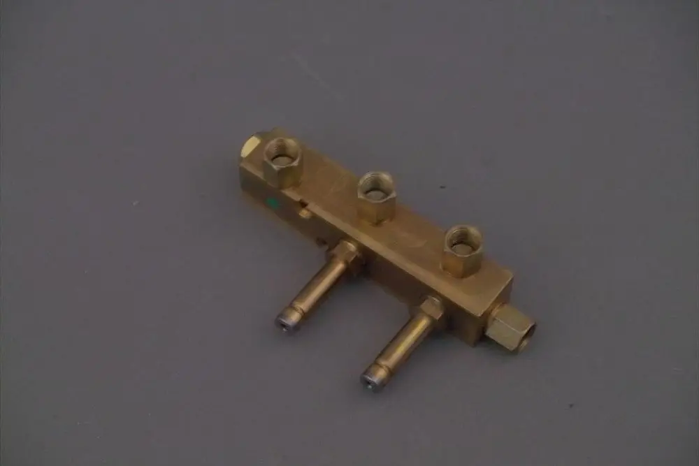 Brötje Magnetventilblock aus Metall mit mehreren Anschlüssen und zwei abgehenden Rohren, auf grauem Hintergrund.