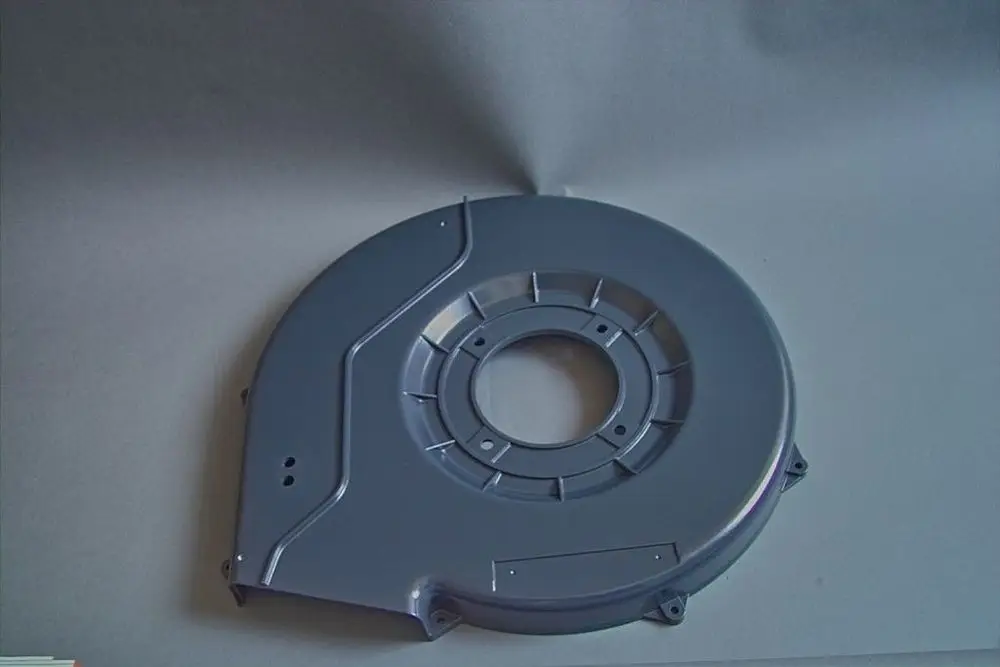 Graue Haube von Brötje mit runder Form und zentraler Öffnung. Die Oberfläche ist glatt und die Kanten sind ausgeprägt. Es sind Montagelöcher sichtbar.