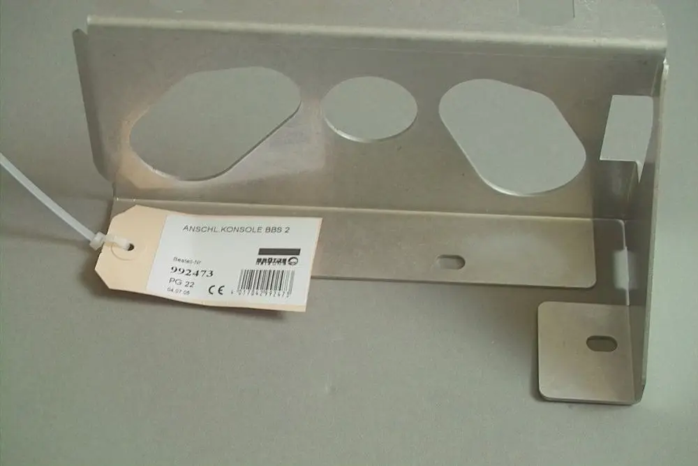 Brötje Anschlusskonsole aus Metall mit mehreren Öffnungen zur Befestigung. An der Konsole befindet sich ein Etikett mit Artikelnummer und weiteren Informationen.