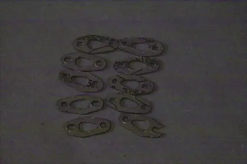 Zeichnung mehrerer Metallkomponenten, möglicherweise Dichtungen oder Halterungen, auf grauem Hintergrund, einige mit aufgedrucktem Text. Brötje ist nicht klar erkennbar.