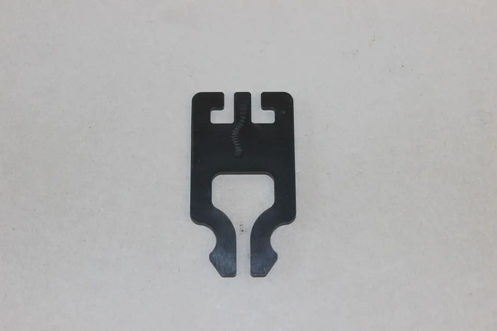 Brötje Halteklammer, flache Metallkonstruktion mit Ausstanzungen an den Seiten. Die Oberfläche ist schwarz und weist eine durchgehende Linie in der Mitte auf.