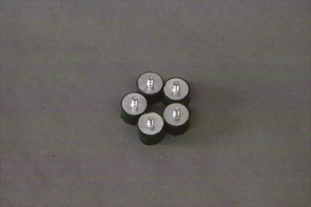 Brötje Abstandshalter in Form von fünf runden, schwarzen Pumpenhaltern mit metallischem Kopf, auf dunklem Hintergrund angeordnet.