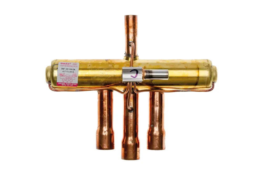 Brötje 4-Wegeventil mit kupfernen Anschlussrohren und einem goldenen Zylinder. An der Seite befindet sich ein Etikett mit technischen Informationen.