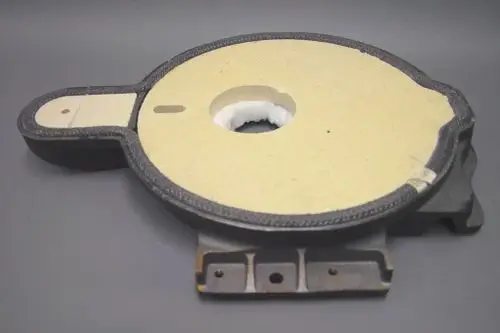 Komponente von Brötje, bestehend aus einer runden Platte mit einem zentralen Loch und einem seitlichen Ansatz. Material und Struktur sind klar erkennbar.