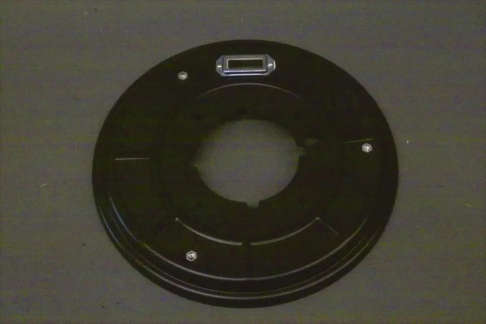 Schwarze Metallplatte mit zentralem Loch und mehreren Schraublöchern, möglicherweise Teil einer Brötje Brennertür oder ähnlicher Anwendung.
