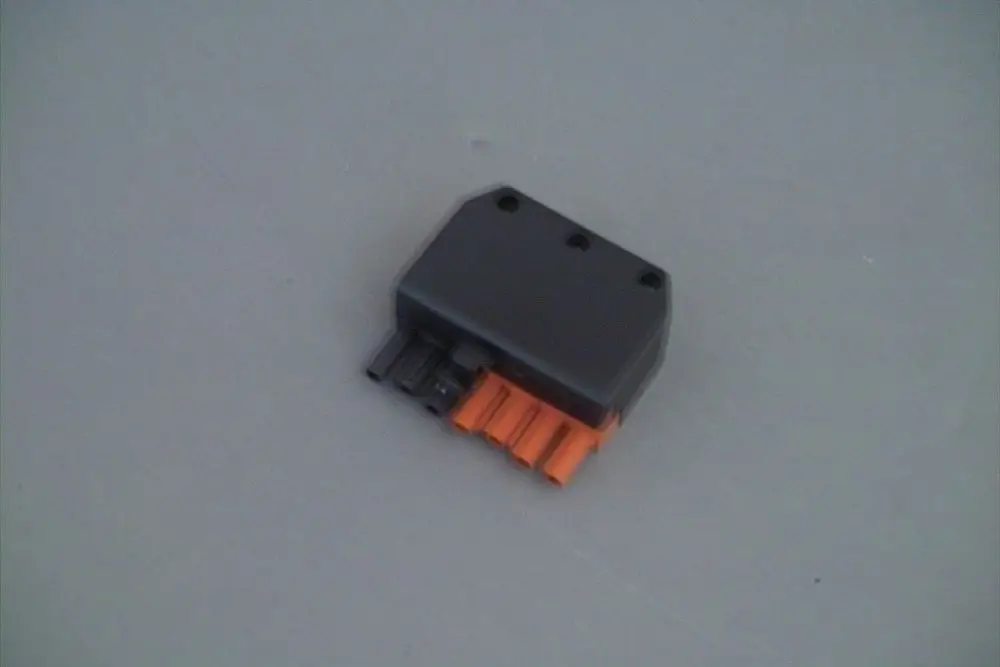 Stecker in schwarzer und oranger Ausführung, mit mehreren Anschlussstiften. Produkt von Brötje, auf grauem Hintergrund abgebildet.