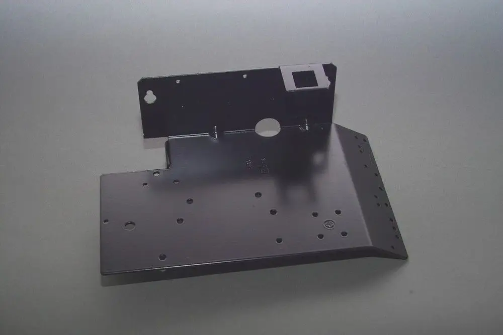 Brötje Halter für Elektrobauteile, aus schwarzem Metall, mit mehreren Löchern und einem rechteckigen Ausschnitt, geeignet zur Montage von elektrischen Komponenten.