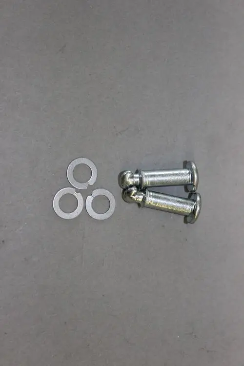 Zwei metallene Schnellverschluss-Schrauben mit runden Köpfen und drei Unterlegscheiben auf grauem Hintergrund, hergestellt von Brötje.