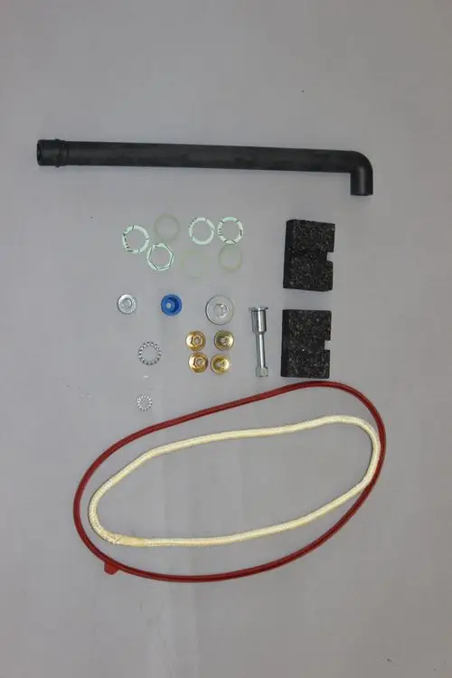 Hintergrund in Grau mit verschiedenen Bauteilen, darunter ein schwarzes Rohr, Riegel, Unterlegscheiben, Dichtungen und eine rote sowie eine weiße Schnur. Teile können für Brötje Produkte verwendet werden.