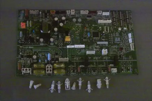 Grüne Leiterplatte von Brötje mit verschiedenen elektronischen Komponenten, Steckplätzen und Display, umgeben von mehreren kleinen Halterungen.