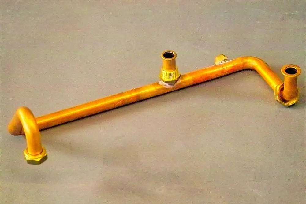 Rücklaufanschlussrohr aus Kupfer mit mehreren Anschlüssen, geeignet für Heizungsanlagen der Marke Brötje. Klar erkennbar sind verschiedene Gewinde und Formen.