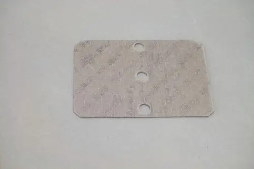 Dichtung aus grauem Material mit drei Löchern, möglicherweise zur Verwendung in Brötje-Produkten, auf einer neutralen Hintergrundfläche.