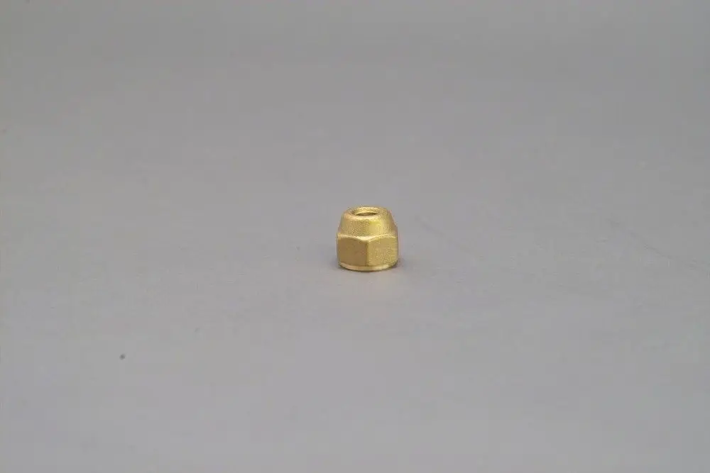 Brötje Verschlusskappe in goldener Farbe, mit einer sechseckigen Form und einer Öffnung in der Mitte, auf grauem Hintergrund abgebildet.