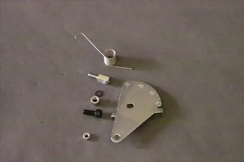 Brötje Scalensegment mit verschiedenen Metallteilen, darunter eine gebogene Feder, Schrauben und eine Metallplatte, auf grauem Untergrund angeordnet.