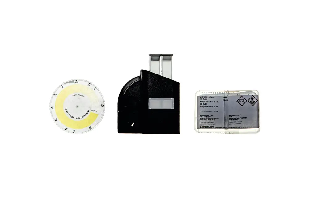 Drei Komponenten eines Brötje-Produktes: ein runder Messring mit Zahlen, ein schwarzes Gehäuse mit Sichtfenster und eine transparente Verpackung mit Sicherheitshinweisen und Symbolen.