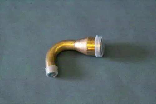 Brötje Einspritzleitung in gebogener Form, mit einer Verbindungsmuffe an einem Ende und einer Öffnung an der anderen Seite. Material ist wahrscheinlich Messing mit Kunststoffteilen.