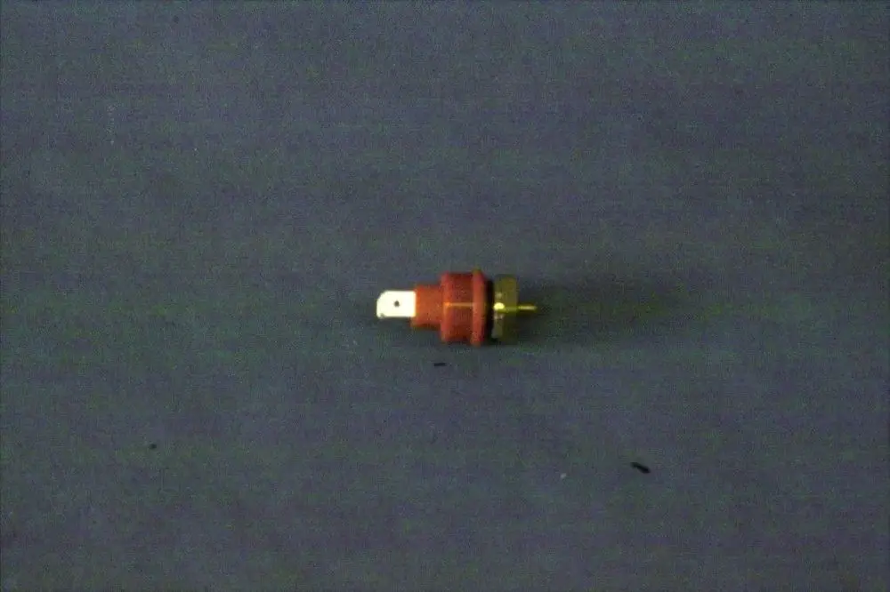 Brötje Temperaturfühler mit rotem Gehäuse und goldfarbenem Anschluss, auf grauem Hintergrund, zeigt eine kabelgebundene Verbindung, generisch ohne spezifische Maße.