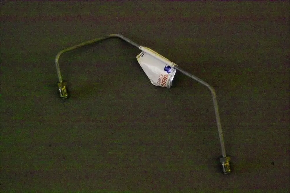 Brötje Öldruckleitung mit zwei Gewindeanschlüssen und einem gebogenen Metallrohr, das eine durchgehende Verbindung darstellt.
