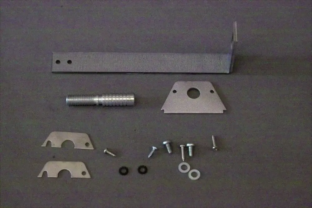 Brötje Halter mit verschiedenen Metallteilen und Schrauben auf grauem Hintergrund. Komponenten sind ein L-Winkel, eine Gewindestange, zwei Bleche und mehrere Schrauben.