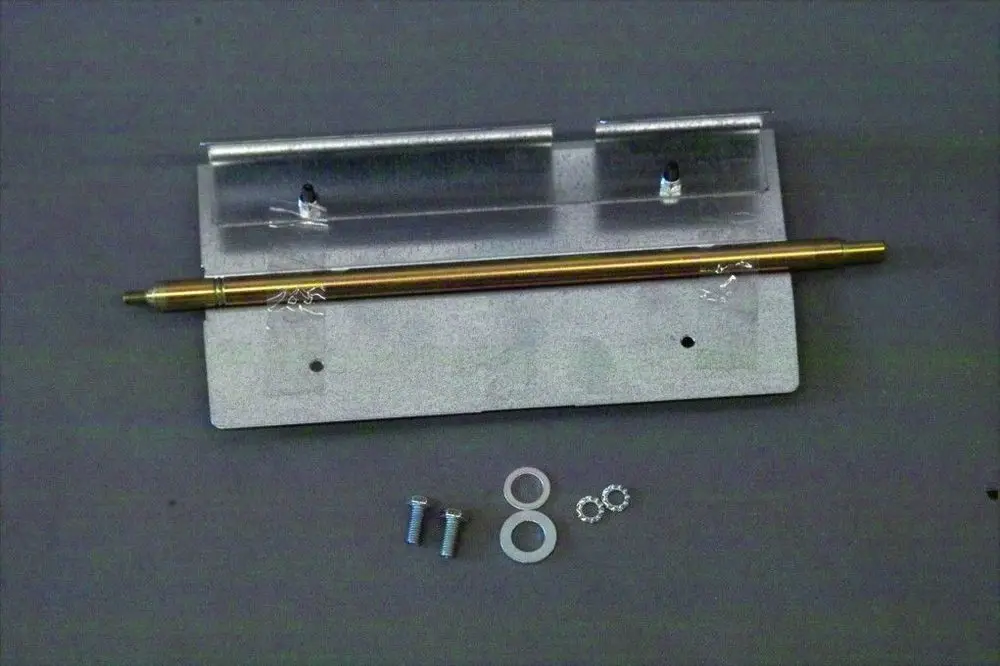 Brötje Luftklappe mit einem Metallhalter, einer goldfarbenen Stange und mehreren Schrauben sowie Unterlegscheiben, auf farbigem Hintergrund angeordnet.