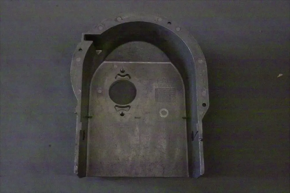 Brötje Ansauggehäuse in metallischer Ausführung mit Ausschnitten und Löchern, möglicherweise für einen technischen Einsatz, auf grauem Hintergrund.