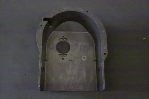 Brötje Ansauggehäuse in metallischer Ausführung mit Ausschnitten und Löchern, möglicherweise für einen technischen Einsatz, auf grauem Hintergrund.