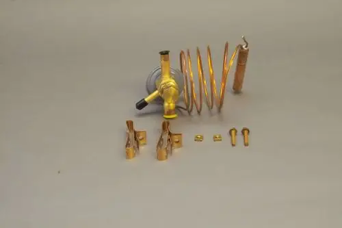 Brötje Expansionsventil mit einer Kupferschlange, einem Kugelhahn und mehreren Montageschrauben sowie Clips im Bild angeordnet auf grauem Untergrund.